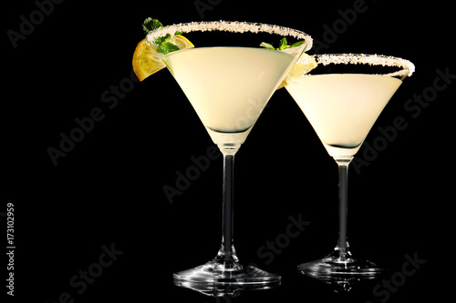 Glasses of lemon drop martini with slices of fruit on black background