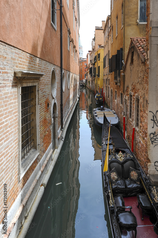 Traditional gondolas in the sea water on background of ancient Venice street, Italy