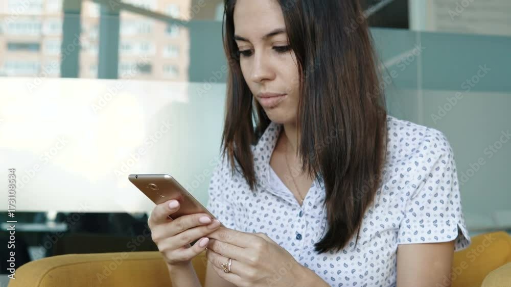 Young smiling woman holding a smartphone in hand and surfing in Internet. Close up of a young woman typing on her smartphone. Young smiling woman holding a smartphone in hand and surfing in Internet. Close up of a young woman typing on her smartphone.
