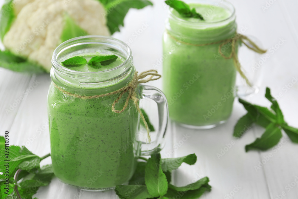 Healthy smoothie with kale in mason jars on wooden table Healthy smoothie with kale in mason jars on wooden table