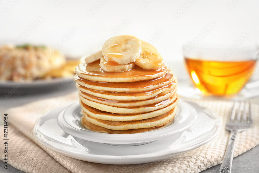 Plate with yummy banana pancakes on kitchen table