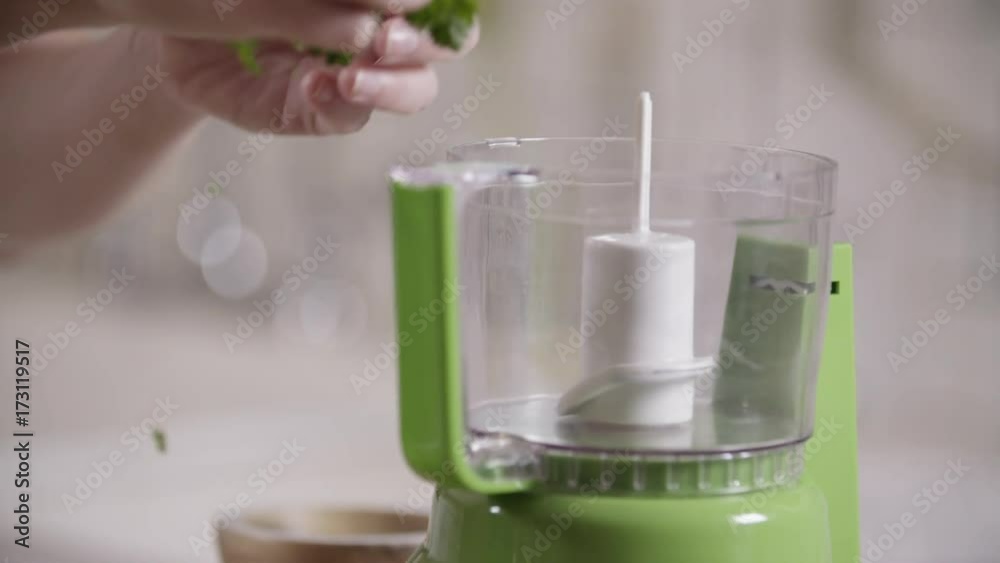 Slow motion, person adds parsley to food processor Slow motion, person adds parsley to food processor