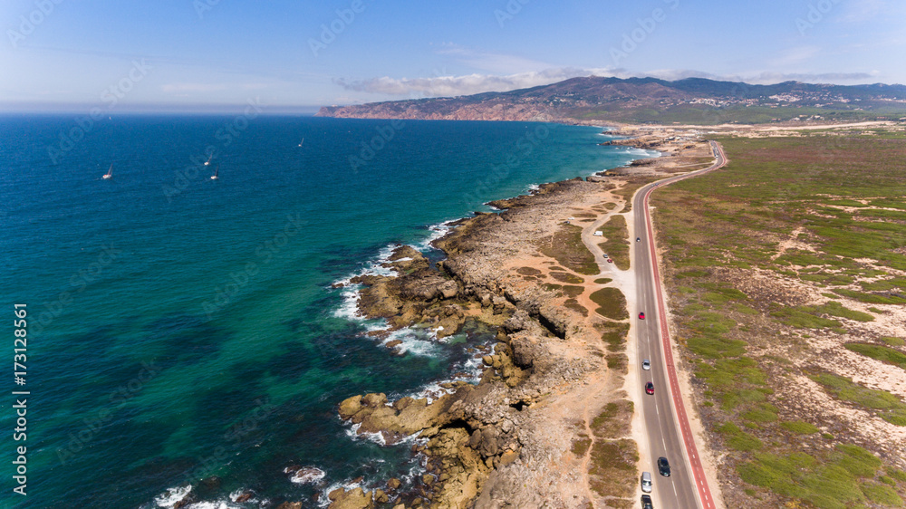 Beautiful road along the coast of ocean on sunny day, Portugal aerial view from Drone