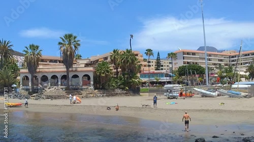 Low flying aerial drone shot of beach over sea in Los Cristianos Tenerife Spain