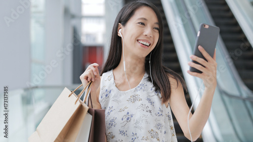 Woman making video call and holding shopping bag