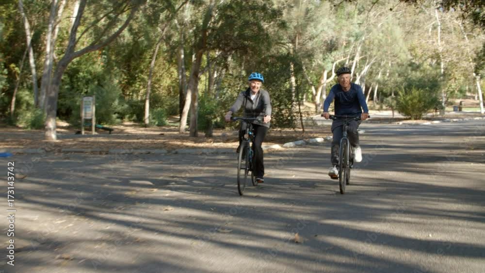 Senior Couple Cycling Through Park In Slow Motion Senior Couple Cycling Through Park In Slow Motion