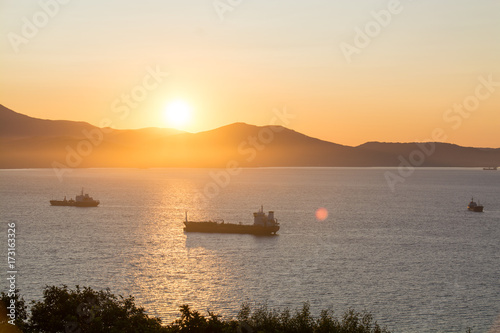 Commercial ships anchored at the bay with golden sunrise in the morning.