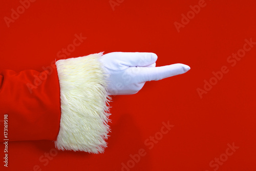 Santa Claus hand presenting your christmas text or product over red background with copy space