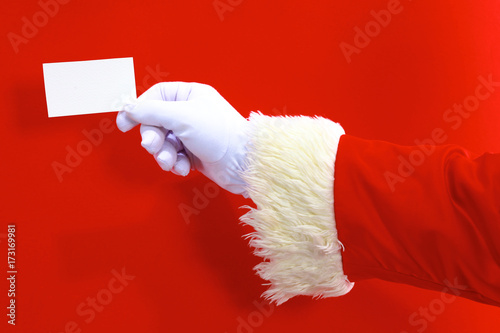 Santa Claus hand presenting your christmas text or product over red background with copy space