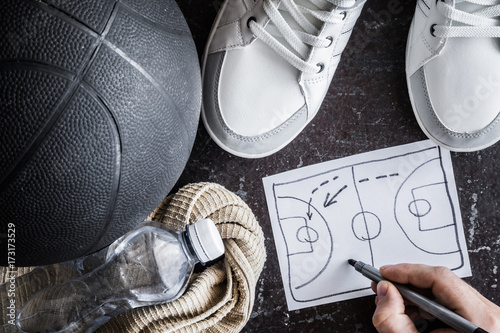 Old, black basketball ball with accessories on the dark floor. Coach creates a game of tactics. Street basketball. Outdoor sport activity. Sport concept. Close up. Vintage retro style and atmosphere. 