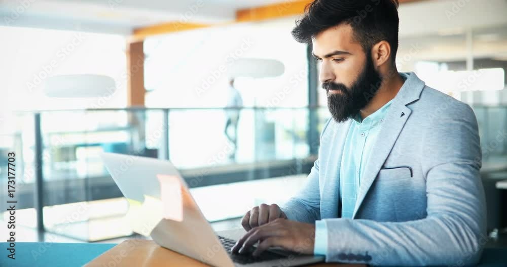 Young handsome architect working on laptop in office