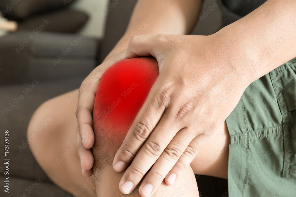 the knee man holds on suffering from pain in knee Closeup. The lesion is highlighted in red. the knee man holds on suffering from pain in knee Closeup. The lesion is highlighted in red.