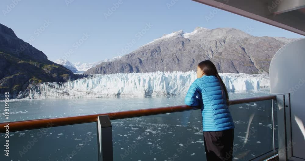 Alaska cruise ship passenger on balcony looking at glacier in Glacier Bay National Park, USA. Woman on travel vacation sailing enjoying view of Margerie Glacier. RED EPIC SLOW MOTION.