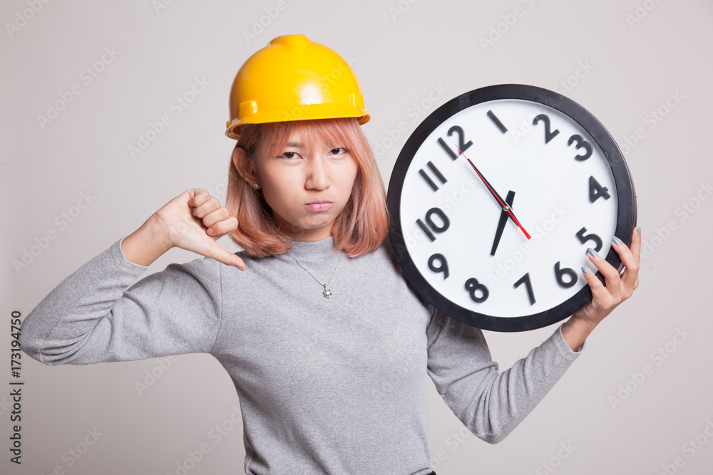 Asian engineer woman thumbs down with a clock. Asian engineer woman thumbs down with a clock.