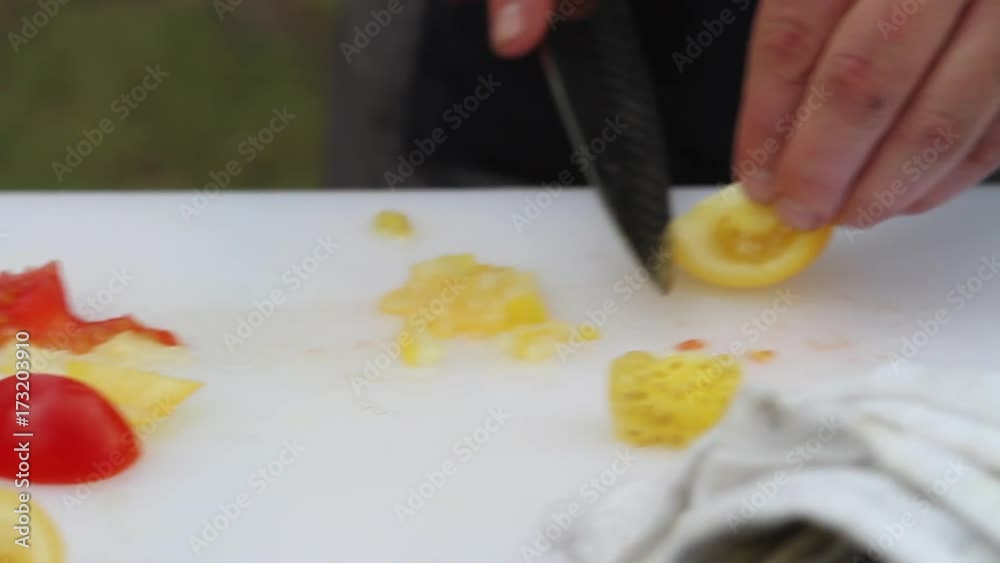 Close up, person cuts tomatoes on cutting board