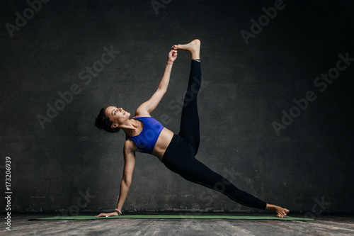 Young beautiful yoga female posing in studio