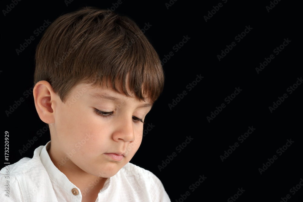 sad little child looking down in a black background sad little child looking down in a black background