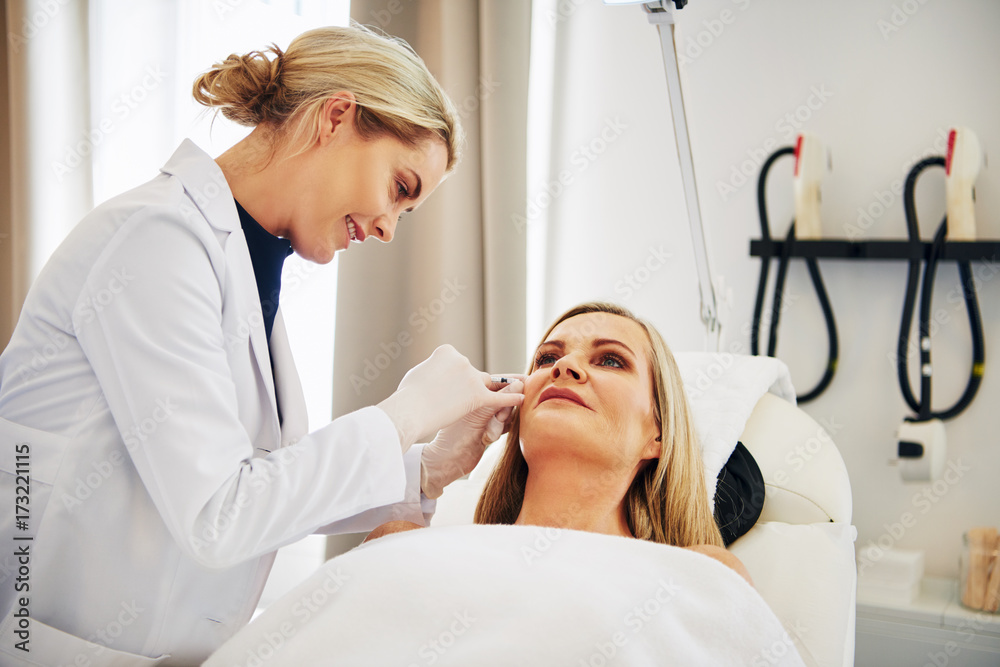 Doctor doing botox injections on a mature woman's face Doctor doing botox injections on a mature woman's face