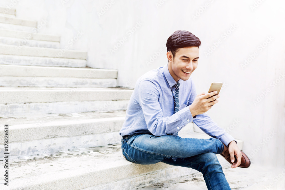 Happy and friendly young Businessman using or Working on Smart Phone and sitting outdoor Stair, Social communicate technology in Business concept, Lifestyle of modern Male Happy and friendly young Businessman using or Working on Smart Phone and sitting outdoor Stair, Social communicate technology in Business concept, Lifestyle of modern Male