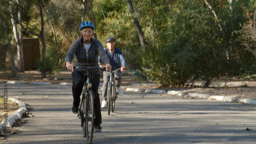 Senior Couple Cycling Through Park In Slow Motion Senior Couple Cycling Through Park In Slow Motion