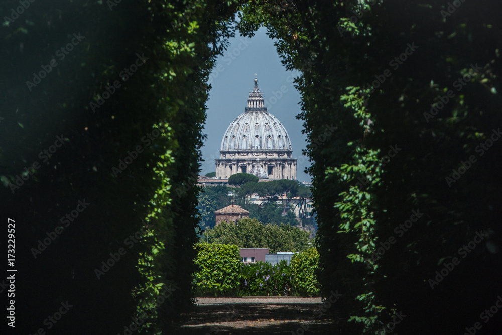 Fototapeta premium The dome of Saint Peters Basilica seen through the famous keyhole at the the gate of the Priory of the Knights of Malta on Aventino Hill. Rome, Italy, Southern Europe