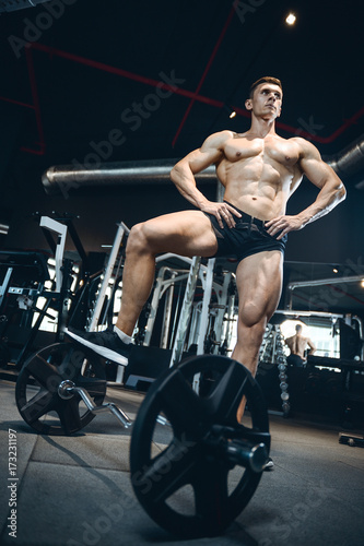 Handsome model young man training legs in gym