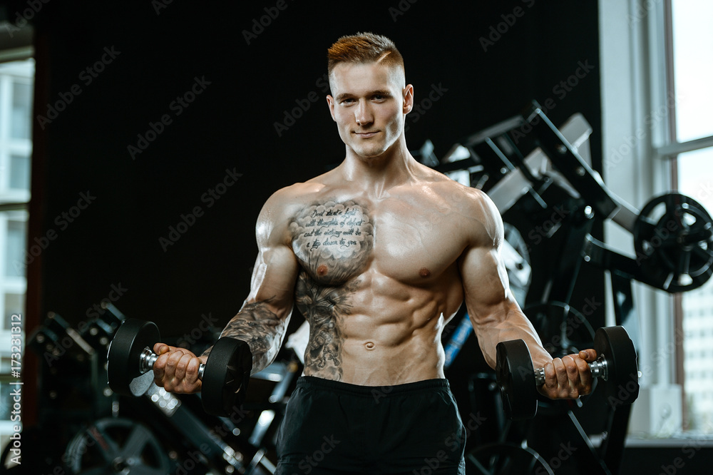 Handsome model young man training arms in gym Handsome model young man training arms in gym