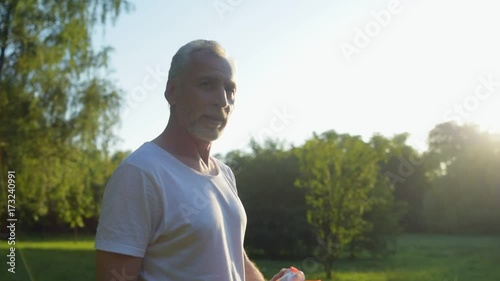 Pleasant aged man drinking water after spoort exercises photo