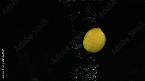 Lemons falling into water on black background. Bright high quality video. photo