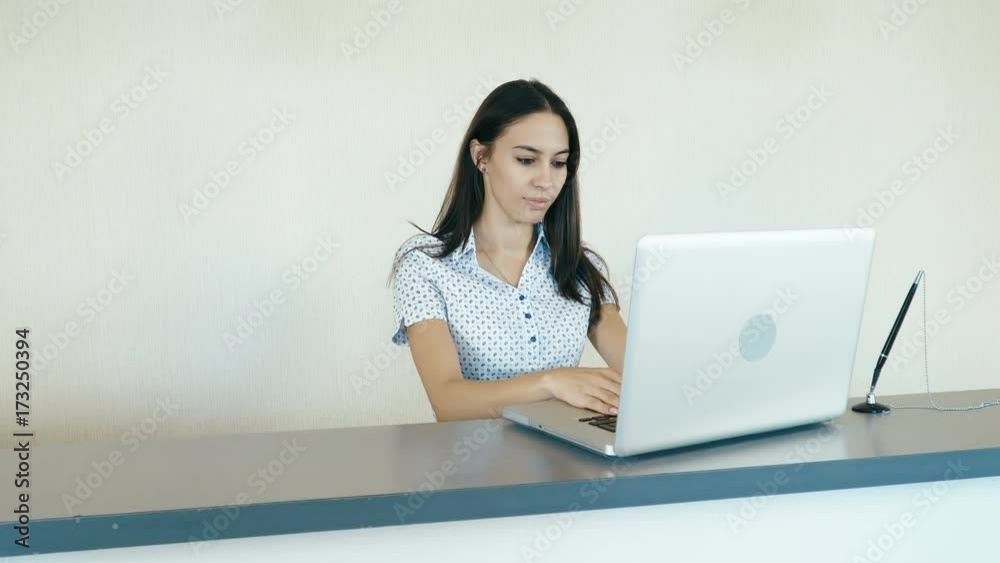 Portrait of a young attractive woman working at the reception or the hotel company. People stock footage slider shot. Portrait of a young attractive woman working at the reception or the hotel company. People stock footage slider shot.