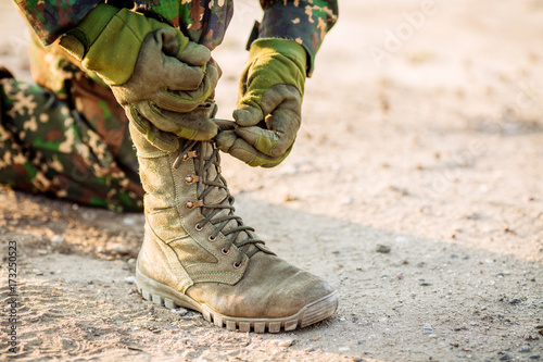 Canvastavla boots and hands tying bootlaces in desert