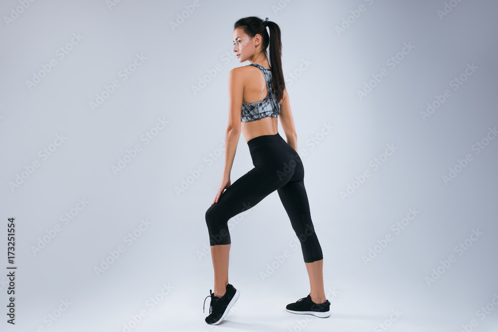Beautiful and sexy sport woman posing as sportwoman back to the camera in studio over gray background Beautiful and sexy sport woman posing as sportwoman back to the camera in studio over gray background