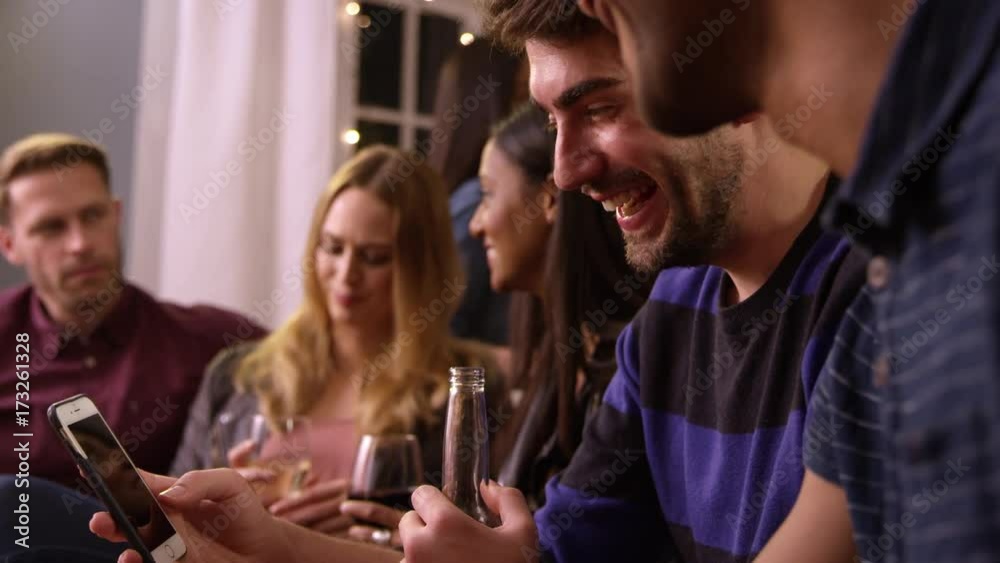 Man Checking Mobile Phone At Party With Friends Man Checking Mobile Phone At Party With Friends