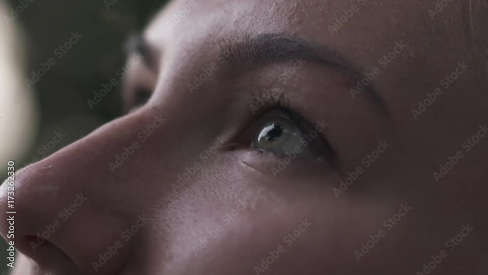 Slow motion handheld closeup teenage girl with green eyes look up on town street in shade
