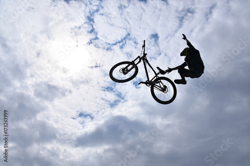 Dark silhouette of freestyle stunt cyclist flying in the sky