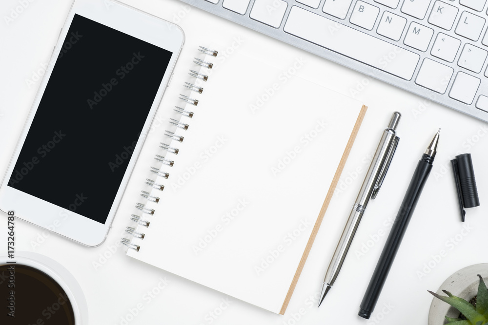 Blank notebook and mobile phone with blank mockup screen are on top of white office desk table. Top view, flat lay. Blank notebook and mobile phone with blank mockup screen are on top of white office desk table. Top view, flat lay.