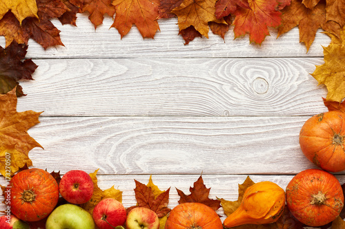 Autumn leaves  apples and pumpkins over wooden background