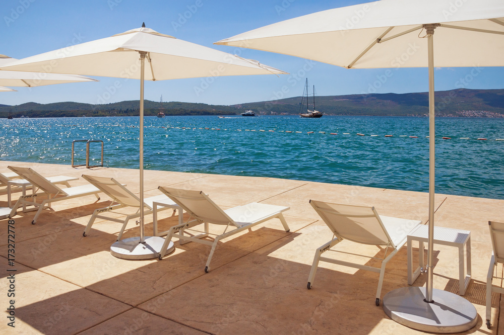 Sun umbrellas and chaise lounges on the beach. Kotor  Bay of Adriatic Sea, Montenegro