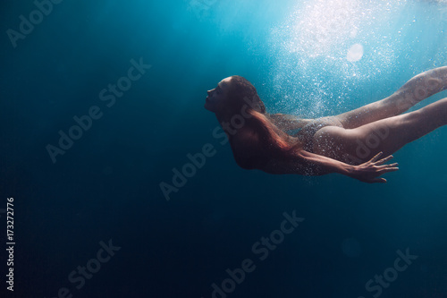 Young woman swimming in sea. Underwater view