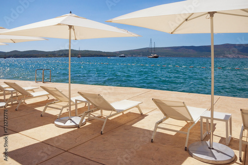 Sun umbrellas and chaise lounges on the beach. Kotor Bay of Adriatic Sea, Montenegro