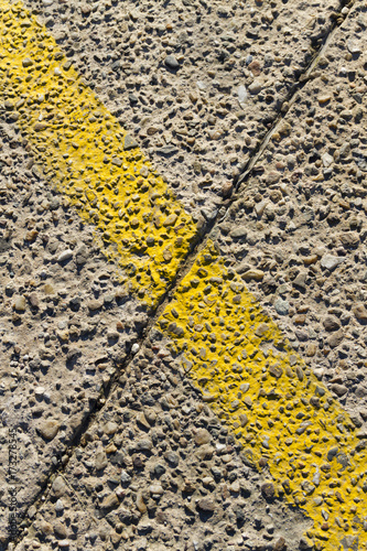 Placemark - concrete path and painted yellow line in cross section with dilatation per diagonal as a sign X; background, texture, pattern, copy space, signboard.