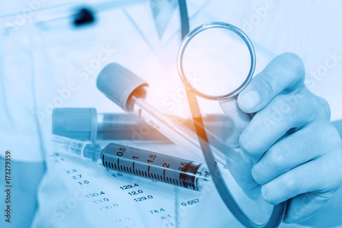 Double exposure of doctor holding stethoscope with Hematology blood analysis report and  lavender color blood sample backgrond.(blue tone)