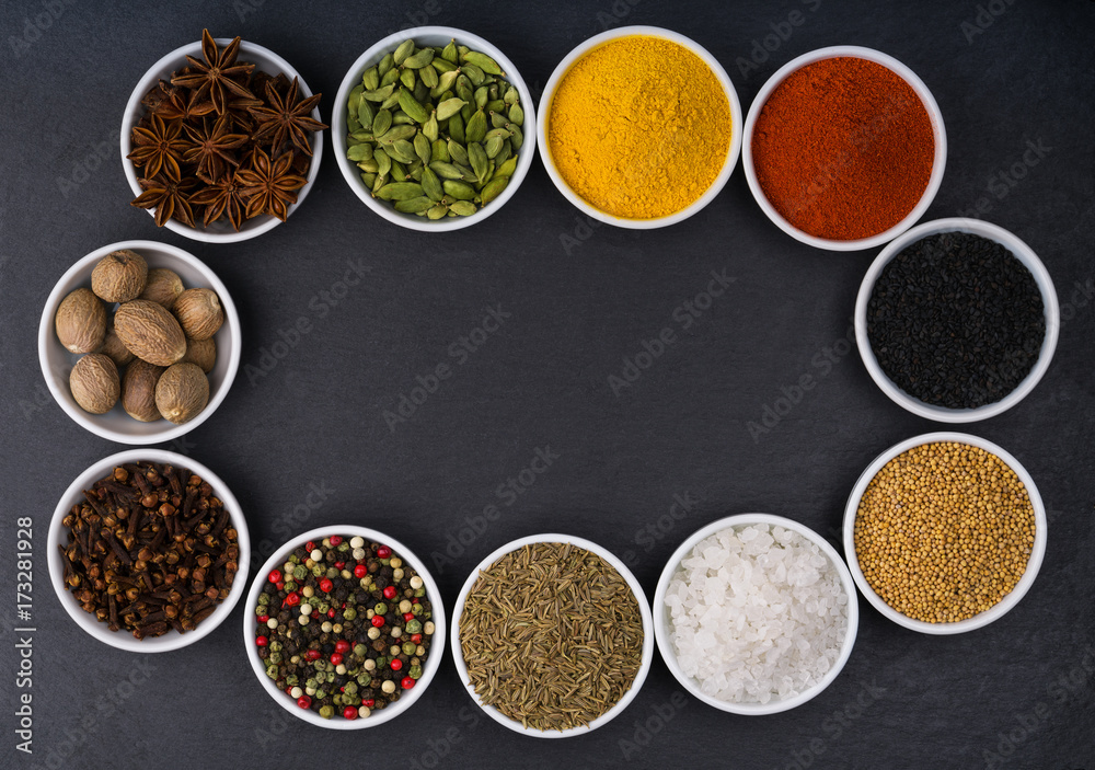 Different spices in ceramic bowls on a black  stone background,top view