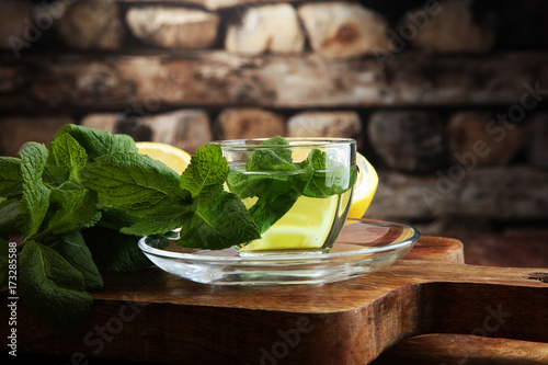 Cup of mint tea and leaves of mint on the table
