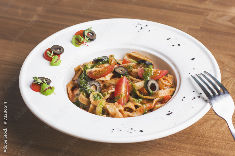 Homemade tomato pasta with olives and pesto