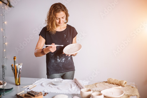 potter woman paints ceramic cup. Woman working In her pottery studio photo