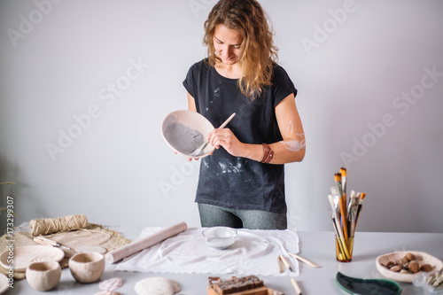 potter woman paints ceramic cup. Woman working In her pottery studio photo