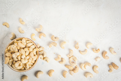 Cashew nuts on a white stone table, in a bowl and scattered. Copy space top view