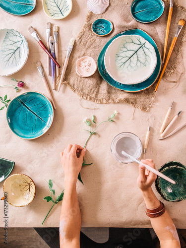 potter woman paints ceramic cup. Woman working In her pottery studio photo