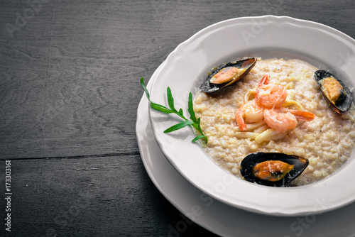 Risotto with seafood, shrimp, mussels and squids and cheese. On a wooden background. Top view. Free space.